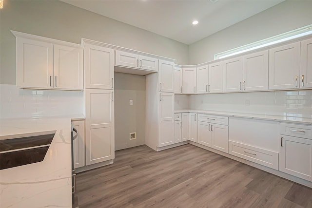 4748 Mallow St, Houston, TX 77033 - kitchen featuring white cabinets, light wood-style floors, backsplash, and light stone counters