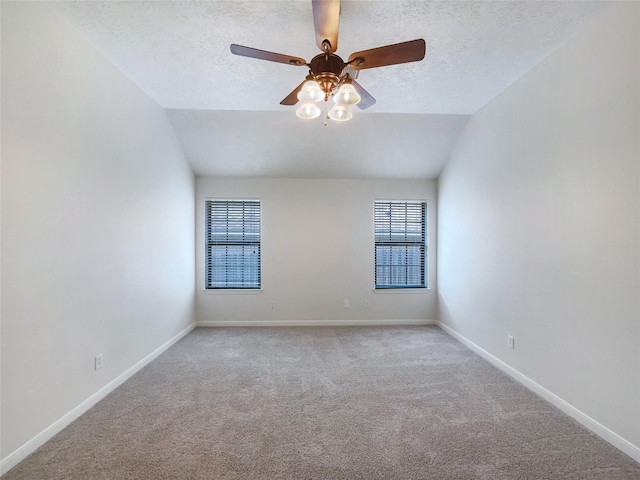 carpeted empty room with a textured ceiling, ceiling fan, and vaulted ceiling