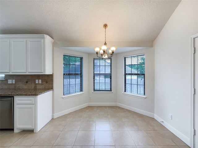 kitchen featuring tasteful backsplash, dark stone counters, decorative light fixtures, dishwasher, and white cabinets