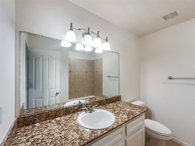 bathroom featuring a tile shower, vanity, and toilet