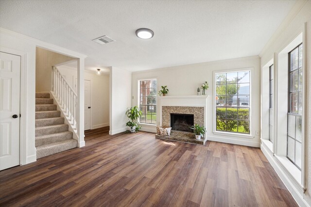 unfurnished living room featuring a textured ceiling, crown molding, and dark wood-type flooring