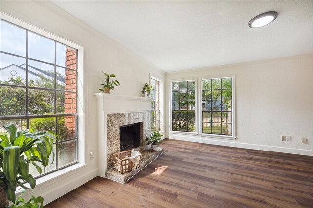 unfurnished living room with crown molding, dark wood-type flooring, and a tiled fireplace