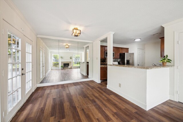 kitchen with french doors, light stone counters, dark hardwood / wood-style floors, kitchen peninsula, and appliances with stainless steel finishes