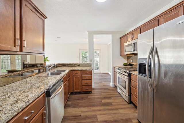 kitchen with a wealth of natural light, dark hardwood / wood-style flooring, light stone counters, and appliances with stainless steel finishes