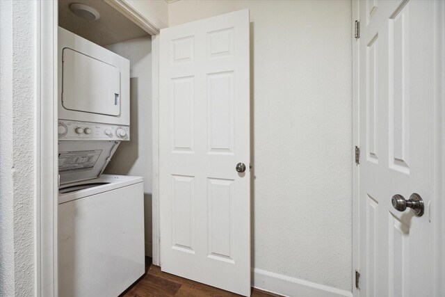 clothes washing area featuring dark hardwood / wood-style flooring and stacked washer and clothes dryer