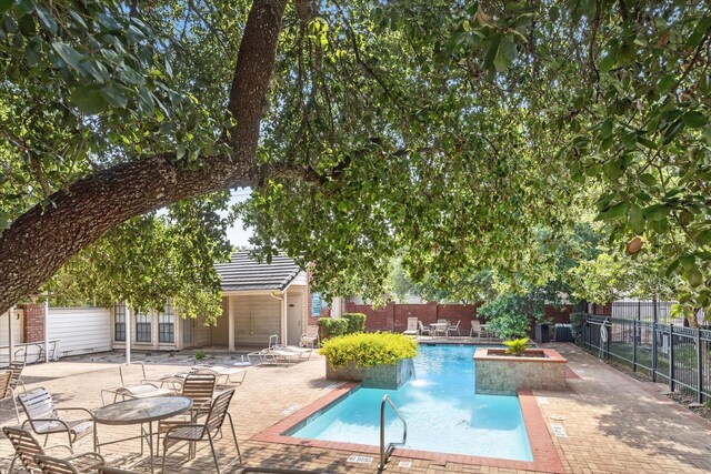 view of swimming pool with pool water feature and a patio area