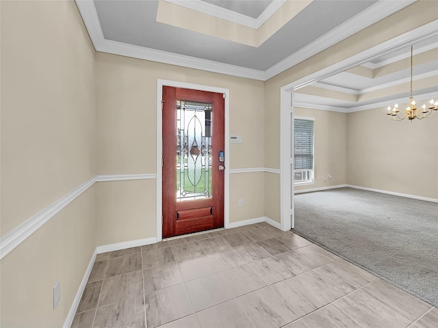 carpeted foyer entrance with a tray ceiling, crown molding, and a notable chandelier