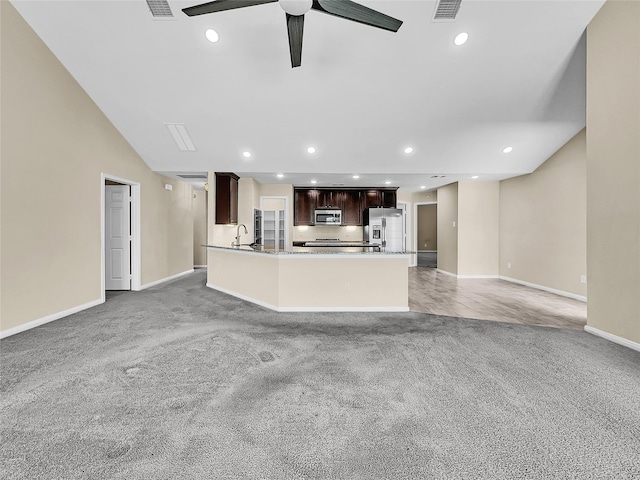 unfurnished living room with ceiling fan, light colored carpet, and sink