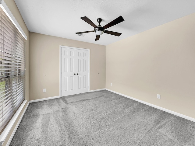 unfurnished bedroom with ceiling fan, carpet floors, a textured ceiling, and a closet