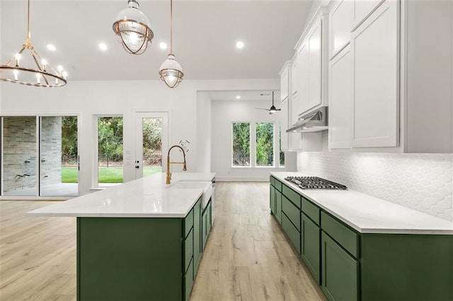 kitchen with white cabinetry, sink, decorative light fixtures, and green cabinets