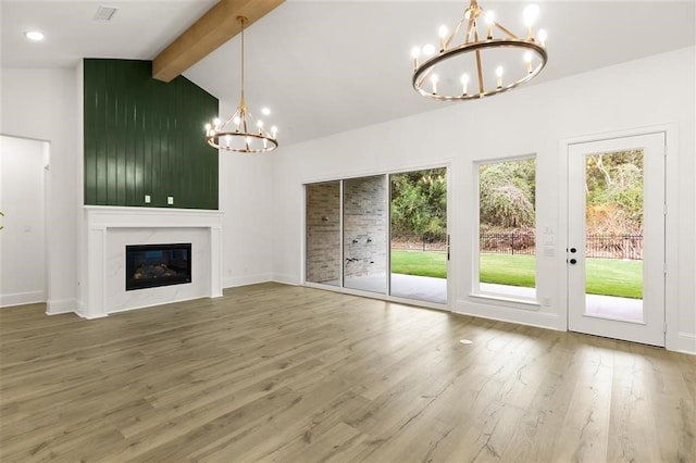 unfurnished living room with hardwood / wood-style flooring, vaulted ceiling with beams, a wealth of natural light, and a notable chandelier