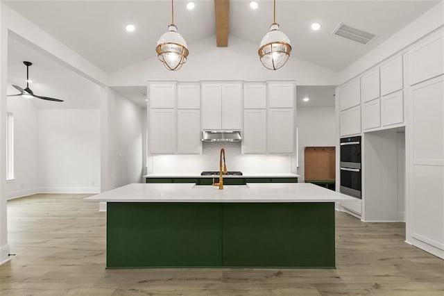 kitchen with pendant lighting, lofted ceiling with beams, an island with sink, and white cabinets