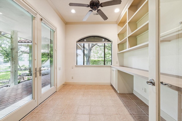 unfurnished office with light tile patterned floors, built in desk, ornamental molding, and ceiling fan