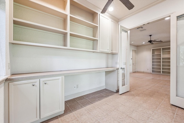 kitchen featuring white cabinetry, crown molding, built in desk, and ceiling fan