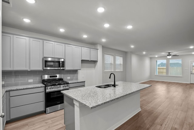 kitchen featuring light hardwood / wood-style flooring, appliances with stainless steel finishes, light stone countertops, and sink