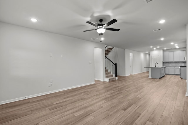 unfurnished living room with ceiling fan, sink, and light hardwood / wood-style floors