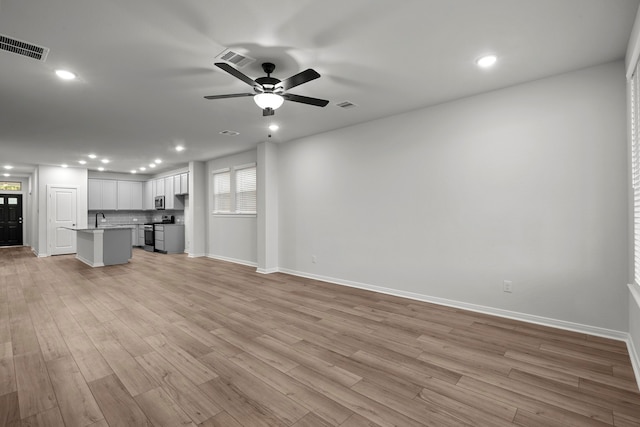 unfurnished living room with light hardwood / wood-style flooring, ceiling fan, and sink