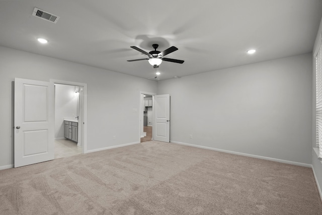 unfurnished bedroom with ceiling fan, light colored carpet, and connected bathroom