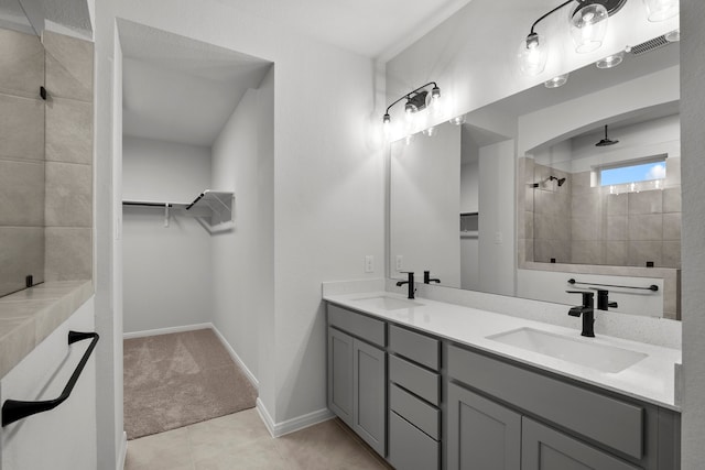 bathroom with vanity, a tile shower, and tile patterned floors