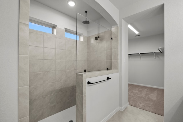 bathroom with tiled shower and tile patterned flooring