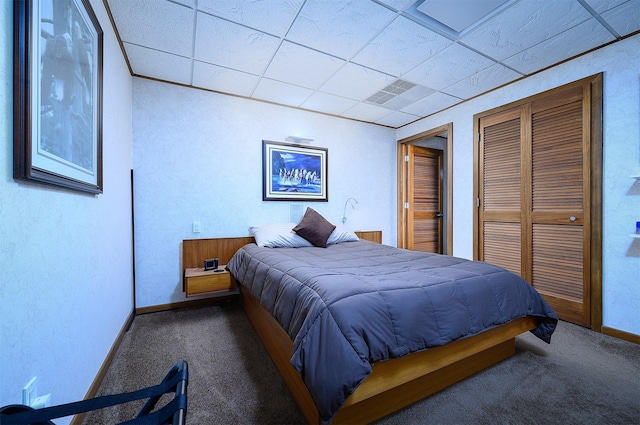 carpeted bedroom featuring a paneled ceiling and a closet