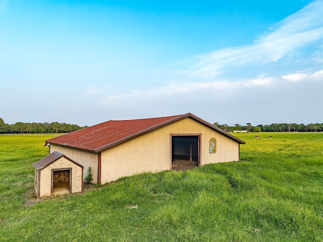 view of side of home featuring a yard, an outbuilding, and a rural view