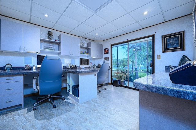 home office with built in desk and a paneled ceiling