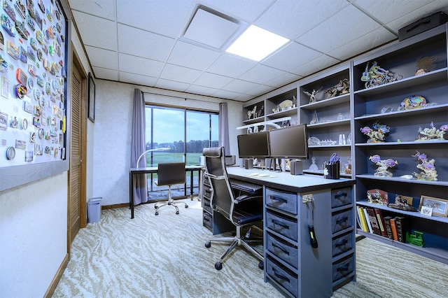 office space with a paneled ceiling and light carpet