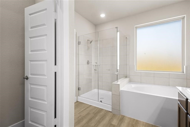 bathroom with wood-type flooring, separate shower and tub, and vanity