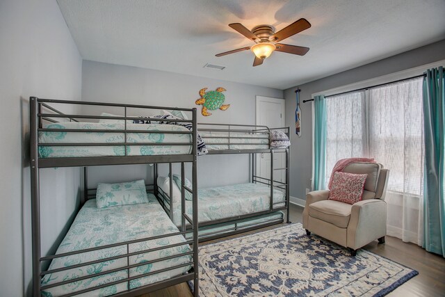 bedroom with ceiling fan, hardwood / wood-style flooring, and a textured ceiling