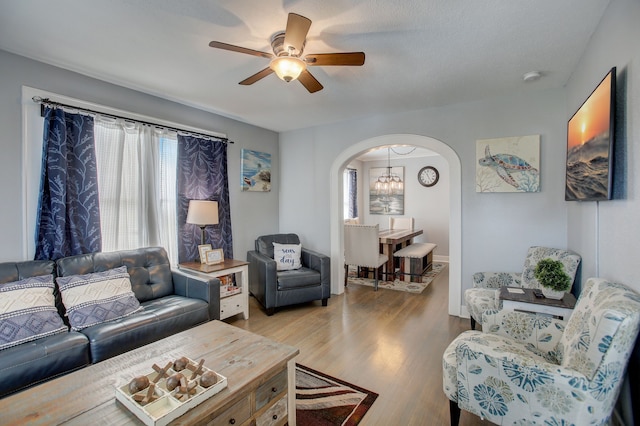 living room with plenty of natural light, ceiling fan with notable chandelier, and light wood-type flooring