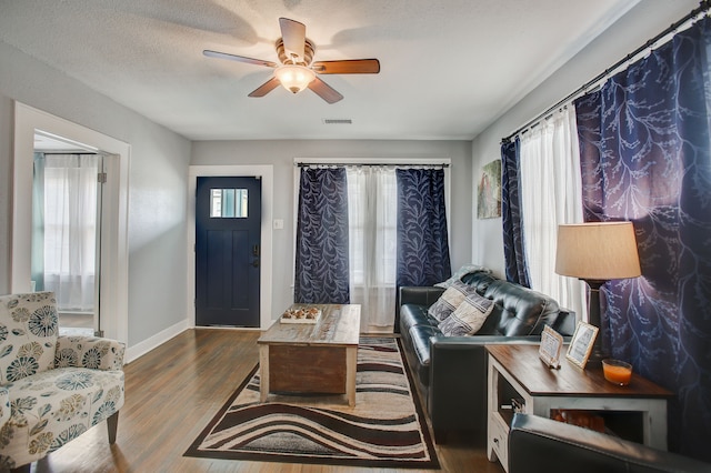 living room with dark wood-type flooring, a textured ceiling, and ceiling fan