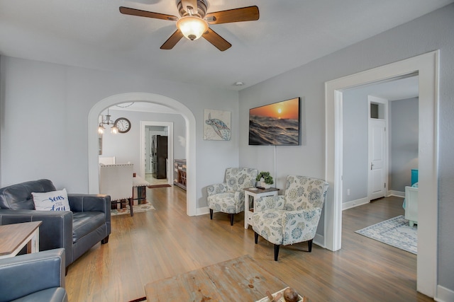 living room with ceiling fan with notable chandelier and hardwood / wood-style floors