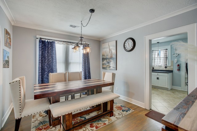 dining room with crown molding, a textured ceiling, hardwood / wood-style flooring, and a notable chandelier