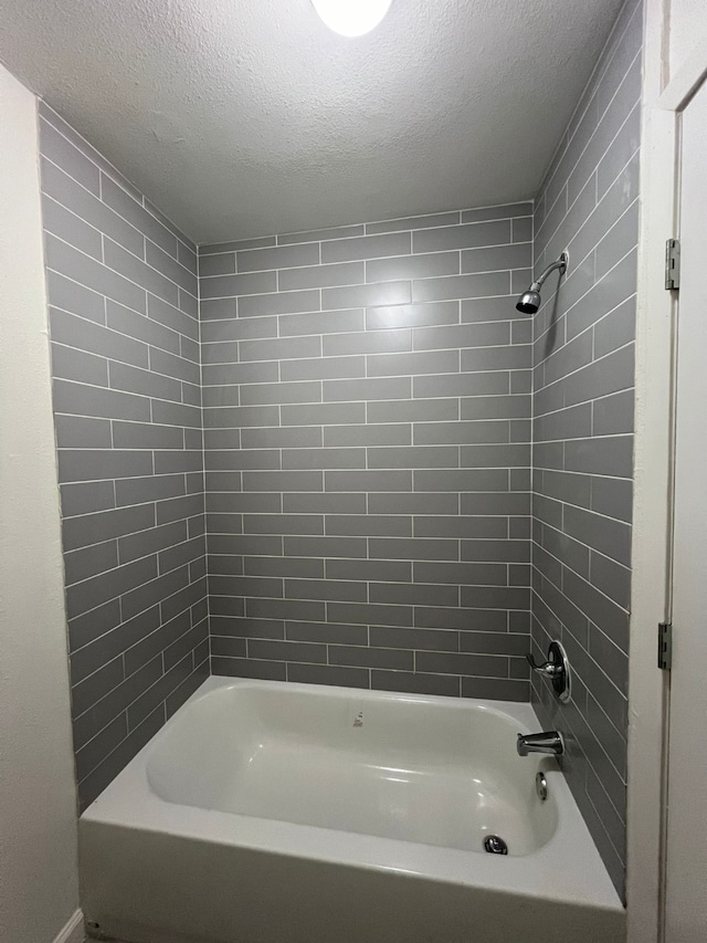 bathroom with tiled shower / bath and a textured ceiling