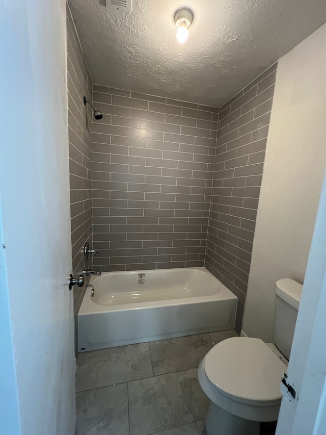 bathroom with tile flooring, a textured ceiling, toilet, and tiled shower / bath combo