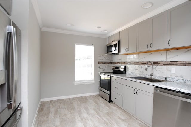 kitchen featuring stainless steel appliances, light hardwood / wood-style flooring, backsplash, and sink