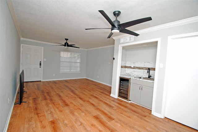 interior space featuring wine cooler, ceiling fan, light wood-type flooring, sink, and ornamental molding