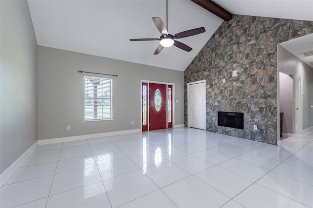 unfurnished living room with a fireplace, beamed ceiling, ceiling fan, light tile patterned floors, and high vaulted ceiling