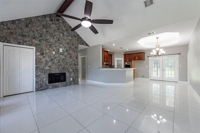 unfurnished living room with french doors, light tile patterned floors, ceiling fan with notable chandelier, a fireplace, and vaulted ceiling with beams