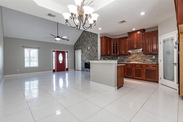 kitchen with ceiling fan with notable chandelier, kitchen peninsula, light tile patterned floors, and tasteful backsplash