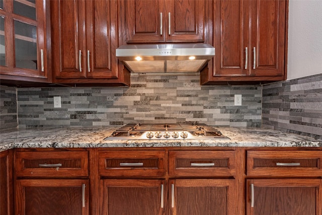 kitchen featuring light stone countertops, stainless steel gas stovetop, and decorative backsplash