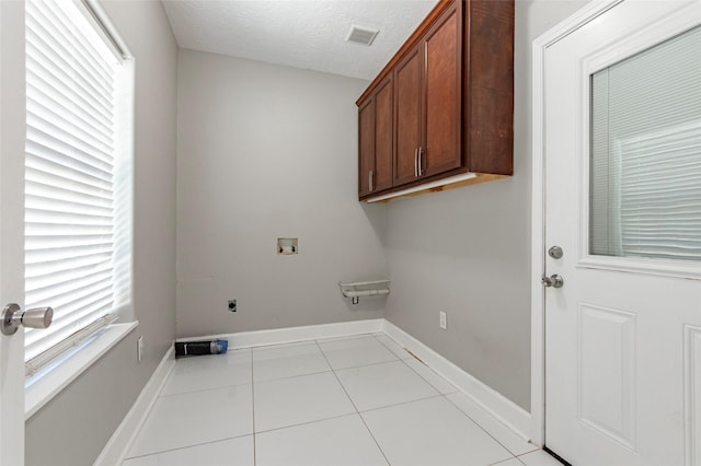 laundry area featuring a textured ceiling, washer hookup, cabinets, hookup for an electric dryer, and light tile patterned floors