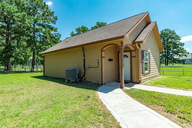 view of front of house with central AC and a front lawn