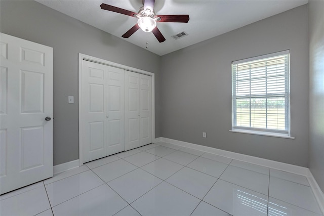 unfurnished bedroom with ceiling fan, light tile patterned floors, and a closet