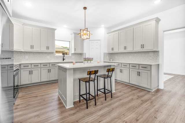 kitchen with decorative light fixtures, a center island, light hardwood / wood-style floors, and gray cabinets