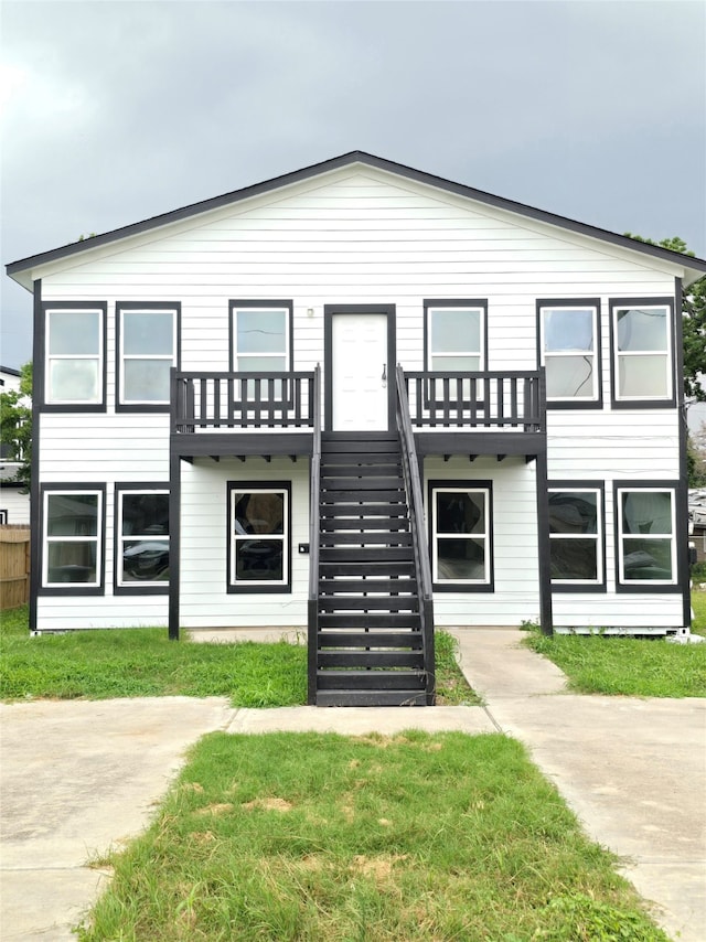 view of front of house with a balcony and a front yard