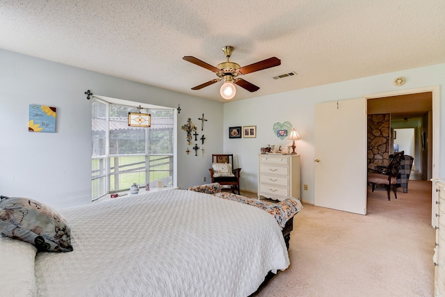 bedroom with light carpet, a textured ceiling, and ceiling fan