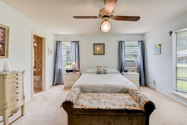 bedroom with multiple windows, light colored carpet, ensuite bath, and ceiling fan