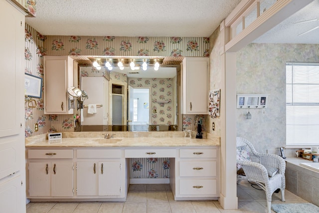 bathroom featuring tile patterned flooring, vanity, a tub to relax in, and a textured ceiling